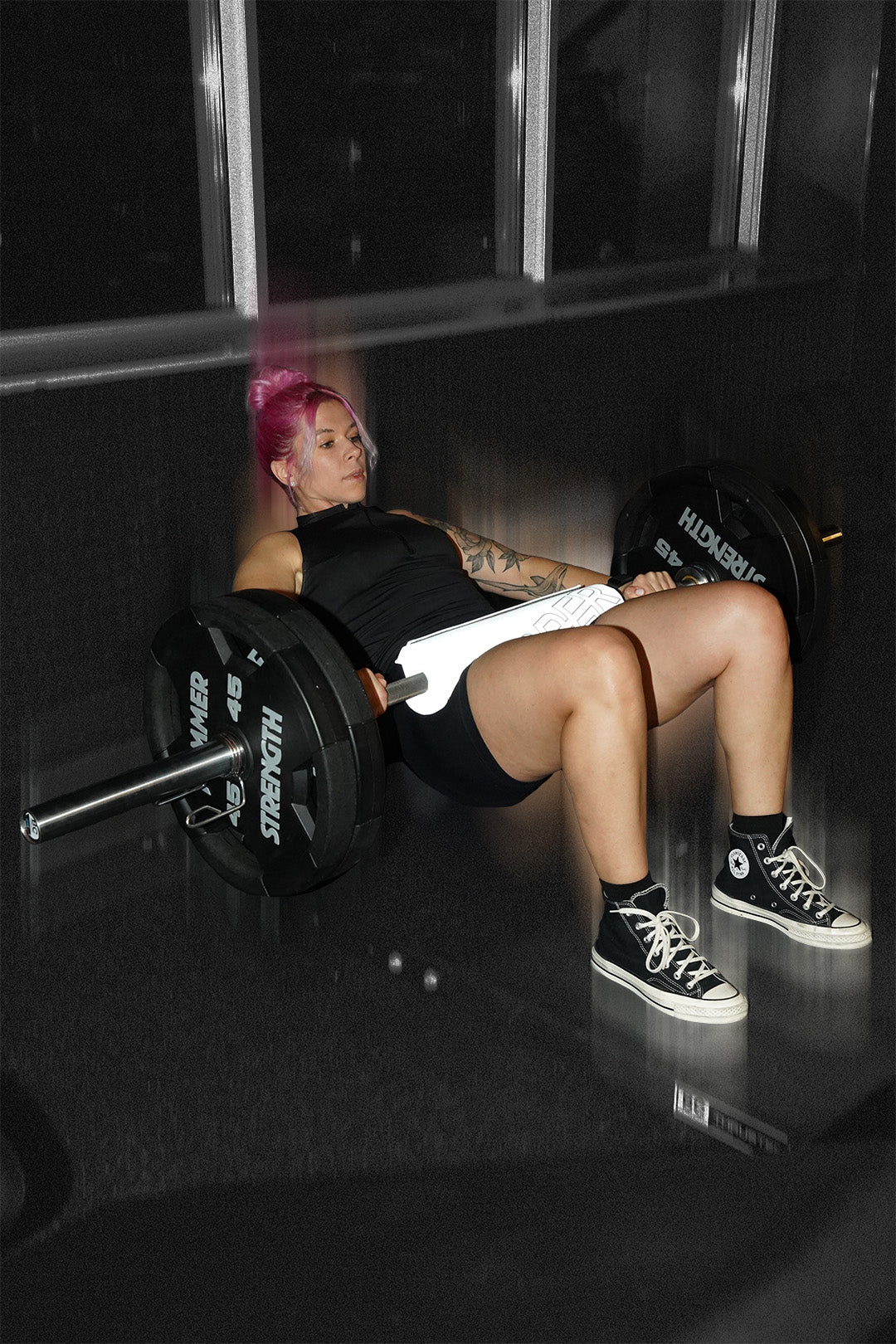 woman doing barbell hip thrusts with uppper barbell pad