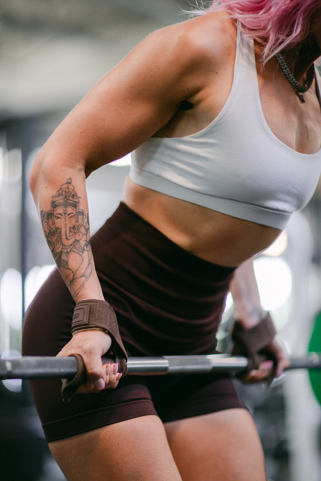 woman doing barbell rows with uppper lifting straps